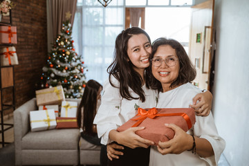 beautiful asian mother and daughter smiling after giving a gift during christmas celebration at home