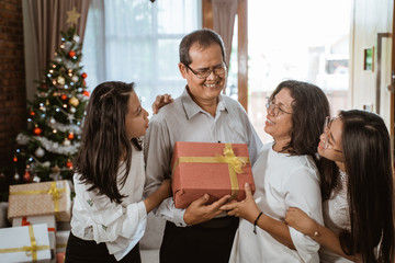 beautiful asian family with two daughter happy gift exchange at home on christmas