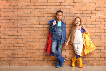 Obraz na płótnie Canvas Fashionable little children in autumn clothes near brick wall