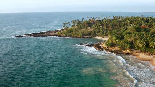 View of the coastal line during sunrise on the southern part of the island of Sri Lanka. Ocean waves, sandy beach and palm trees