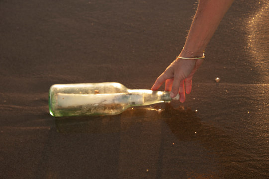 Message In A Bottle. Grunge note rolled inside a vintage bottle washed up on the seashore. 