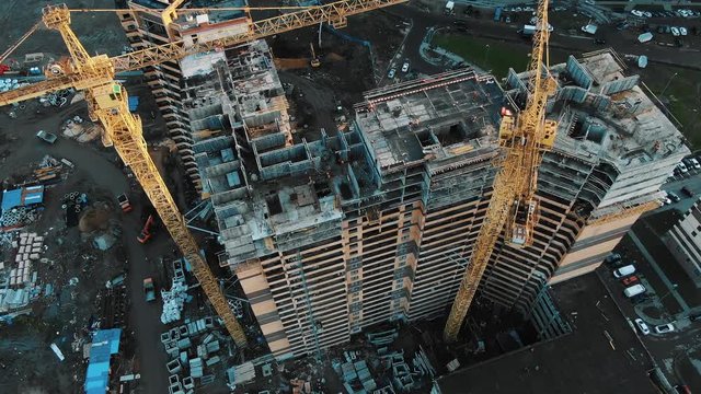 yellow construction cranes above skyscrapers aerial motion