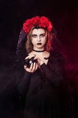 girl witch in a wreath of red roses - 303909134