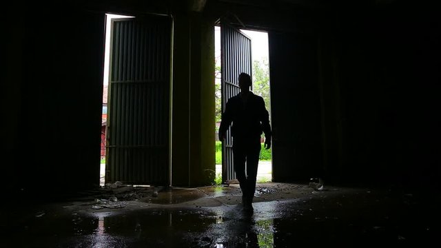 Mysterious man walking in dark, spooky, abandoned building 