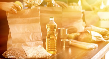 Team of volunteers collecting food donations at table in sunlit room, closeup