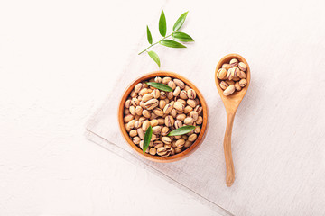 Fototapeta na wymiar Bowl and spoon with tasty pistachio nuts on table