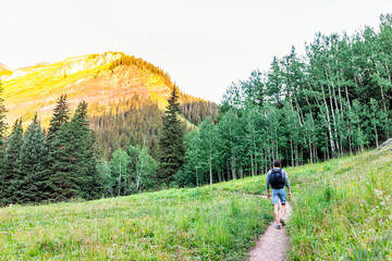 Man walking on green alpine meadow footpath trail to Ice lake near Silverton, Colorado in August...