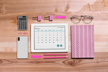 Flat lay composition of tablet with calendar app on wooden table