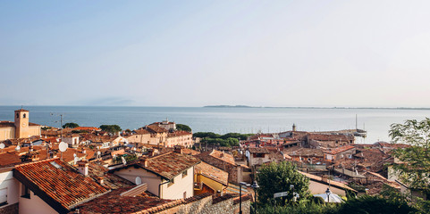 DESENZANO DEL GARDA, ITALY - October 15, 2017: Panorama of the city on a sunny autumn day. Red tiled roofs of an Italian city. View of Lake Garda and the city at sunrise.