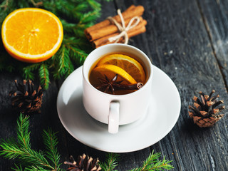 Obraz na płótnie Canvas Mug of black tea with orange and cinnamon. Winter hot drink on wooden table