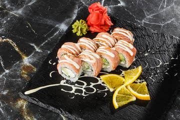 Sushi Rolls with flamed salmon, cucumber and Cream Cheese inside on black slate isolated on black marble background. Philadelphia roll sushi with cucumber. Sushi menu. Horizontal photo.