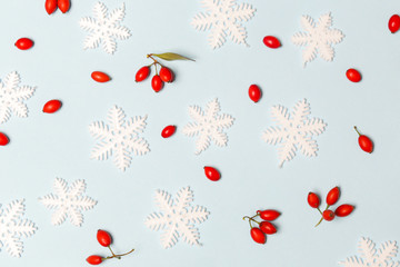 Christmas pattern made of snowflakes and red berries on pale blue background. Christmas, winter holiday, new year concept.	