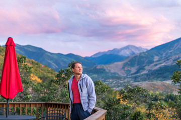Fototapeta na wymiar Aspen, Colorado rocky mountains colorful purple blue twilight sunset view and young man standing by deck wooden terrace railing in autumn