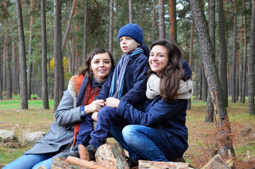 A woman with a baby smiling sitting on logs in the Park.