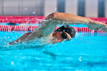 Swimmer man doing crawl swim in swimming pool portrait. Closeup of athlete wearing goggles,...