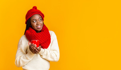 Interested afro girl enjoying hot drink over yellow background