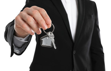 Real estate agent holding house key with trinket on white background, closeup