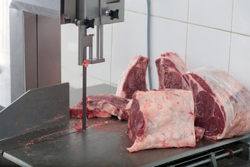 band saw cuts meat in a meat shop - Powered by Adobe