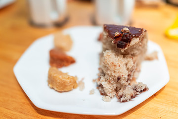 Closeup of slice of yellow vanilla dessert homemade sponge cake with chocolate frosting and coconut macaroons on table