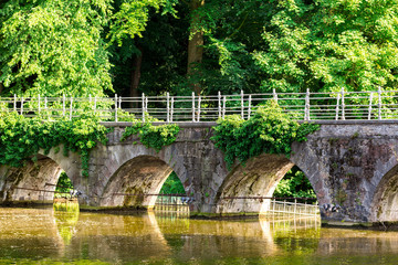 Fototapeta na wymiar Park with stone bridge, old European town