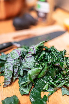 Chopping board with chopped green red kale leaves in kitchen vegetables for healthy meal cooking preparation and knife in background