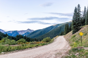 View of green alpine mountains with dirt road leading to Ophir pass near Columbine lake trail in Silverton, Colorado in 2019 summer morning