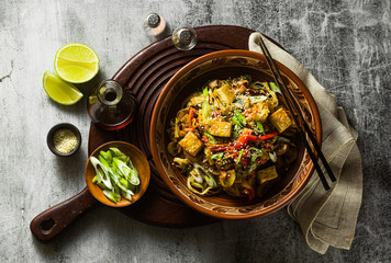 Asian vegan stir fry with tofu, rice noodles and vegetables, top view.