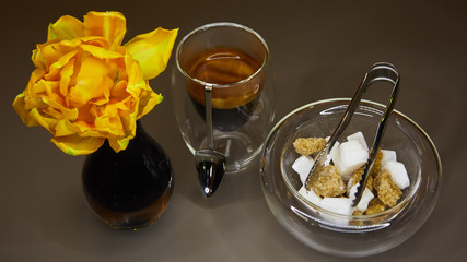 Cup of espresso coffee, sugar and yellow tulip.