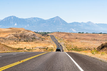 Road highway 92 in Delta, Colorado near Montrose towards Paonia with dry desert landscape view and rocky mountains with cars on street traffic