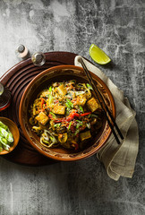 Obraz na płótnie Canvas Asian vegan stir fry with tofu, rice noodles and vegetables, top view.