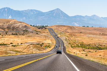 Road highway 92 in Colorado near Montrose towards Paonia with dry desert landscape view and rocky mountains with cars on street traffic