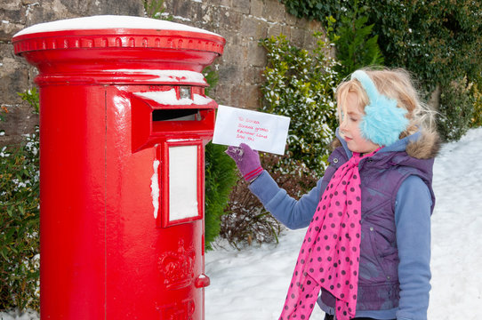 Young girl in a snow covered scene about to post her Christmas letter to Santa