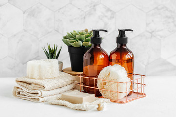 Soap and shampoo bottles and cotton towels with green plant on white table inside a bathroom background. - obrazy, fototapety, plakaty