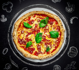 Tasty Italian pizza with basil on black stone background, top view.