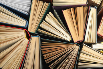 Many different hardcover books on dark background, top view