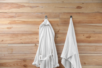Obraz na płótnie Canvas Soft comfortable bathrobe and towel hanging on wooden wall