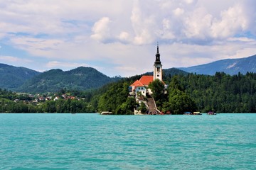 View on a cloudy day to Bled Island on Lake Bled. Boats arriving at church