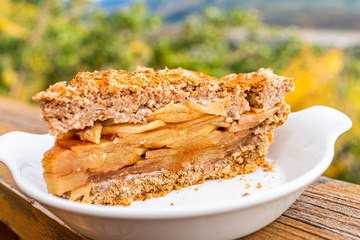 Outside deck balcony terrace wooden railing and macro closeup of plate with slice portion of apple pie baked vegan dessert with fruit filling and golden crust