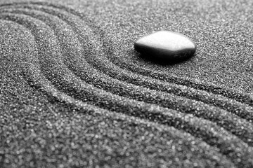 Obraz premium Zen garden stone on black sand with pattern, closeup