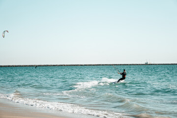 Professional kiter rides on the waves, jumps on the sea.