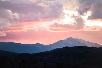 Naklejka na ściany i meble Pink purple red soft light glow sunrise in Aspen, Colorado with rocky mountains peak and vibrant color of clouds at twilight with mountain ridge silhouette