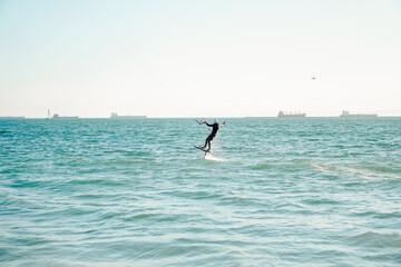Fototapeta na wymiar Professional kiter rides on the waves, jumps on the sea.