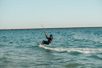 Professional kiter rides on the waves, jumps on the sea.