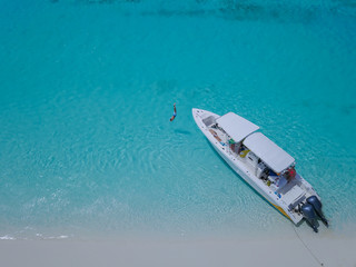 Beautiful view of Bahamas islands from above - child is jumping in the crystal clear sea from the...