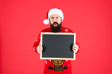 Christmas is coming. Hipster hold santa wish list blackboard. Bearded man with blank advertising blackboard. Blackboard for santa school information. Blackboard for New Year advertisement, copy space