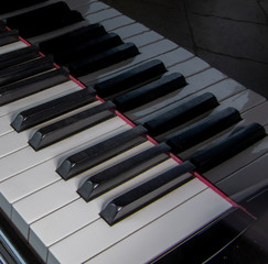 Piano keys reflected on a black shiny baby grand piano, ivory, ebony