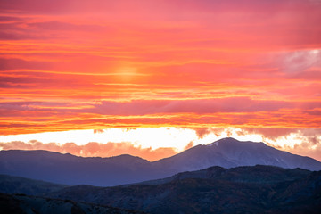 Obraz premium Aspen, Colorado rocky mountains vibrant vivid colorful red sunset orange yellow light in sky with clouds and mountain ridge silhouette