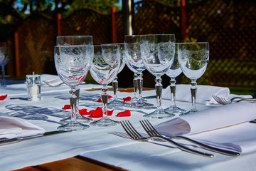 Fine dining table setting with white china and wine and water crystal glasses, with silverware in the order of use, and romantic red tablecloth ready for guests at an event, wedding or at a restaurant