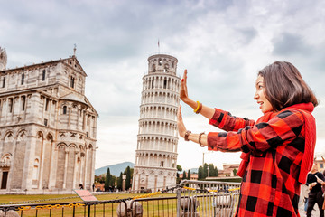 Funny Asian girl supporting famous leaning tower in Pisa. Travel concept - Powered by Adobe