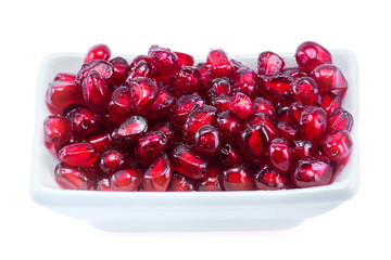 peeled pomegranate seeds in a cup along with a fraction of fresh pomegranate isolated on white background